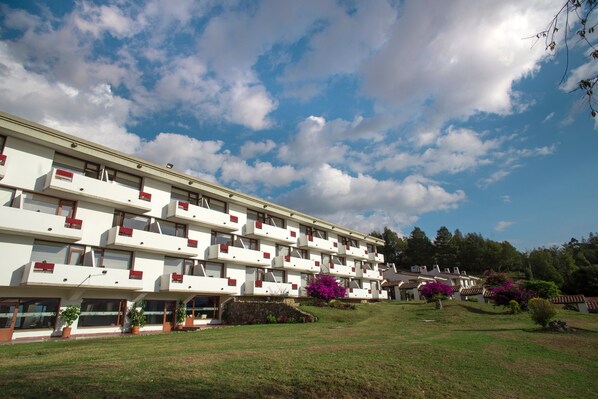 Ein mehrstöckiges Hotel mit Balkonen, einem gepflegten Rasen und umgebender Bepflanzung.