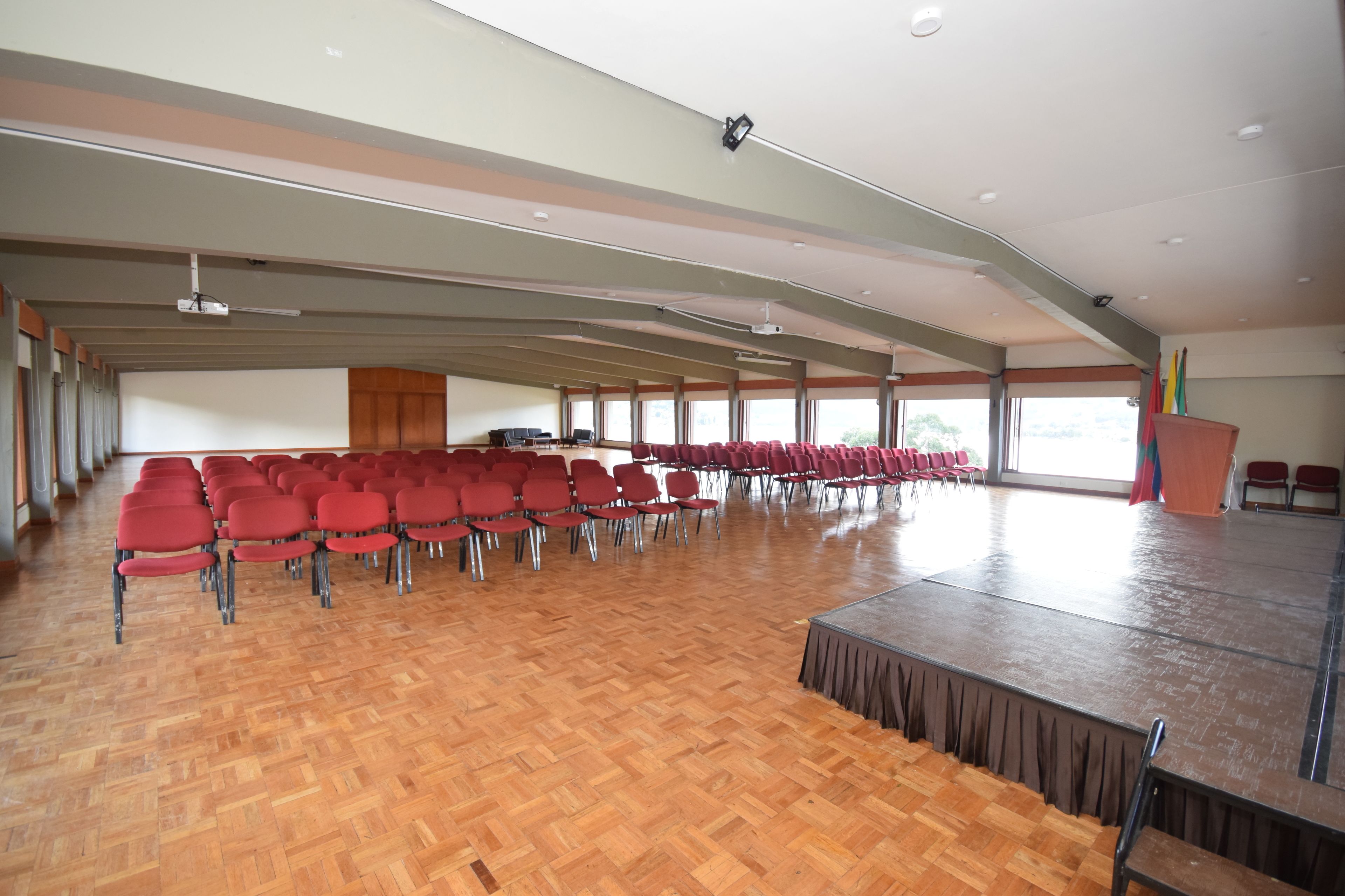A large hall with rows of red chairs and a stage.
