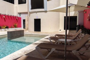 Un espace piscine équipé de chaises longues et d’un parasol.