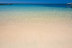 A clear beach with a wooden pier extending into the water. - West EndSunset Villas 10B (Roatan)