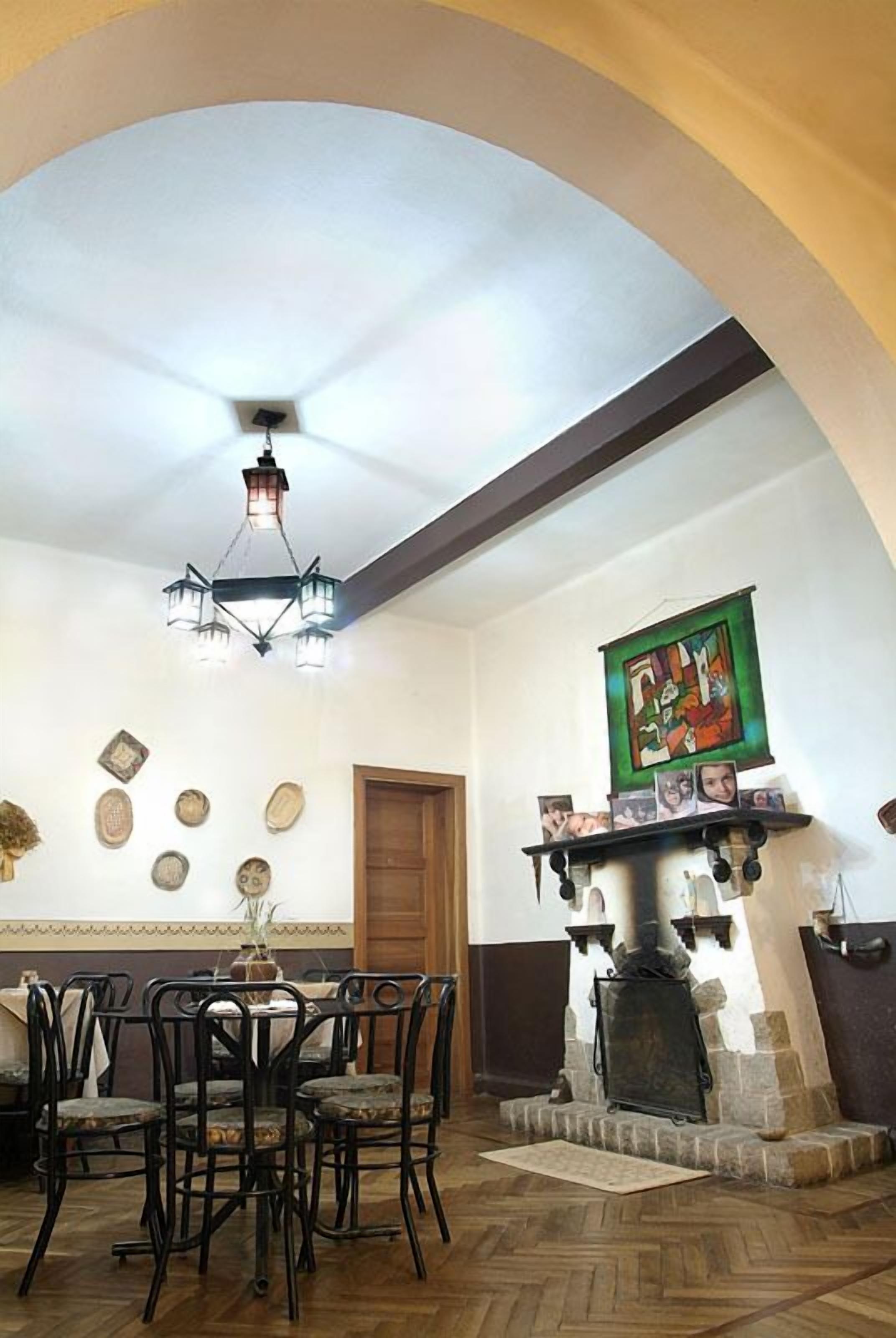 Un coin repas agrémenté d’un lustre, d’une cheminée et d’un mur décoré de tableaux encadrés.