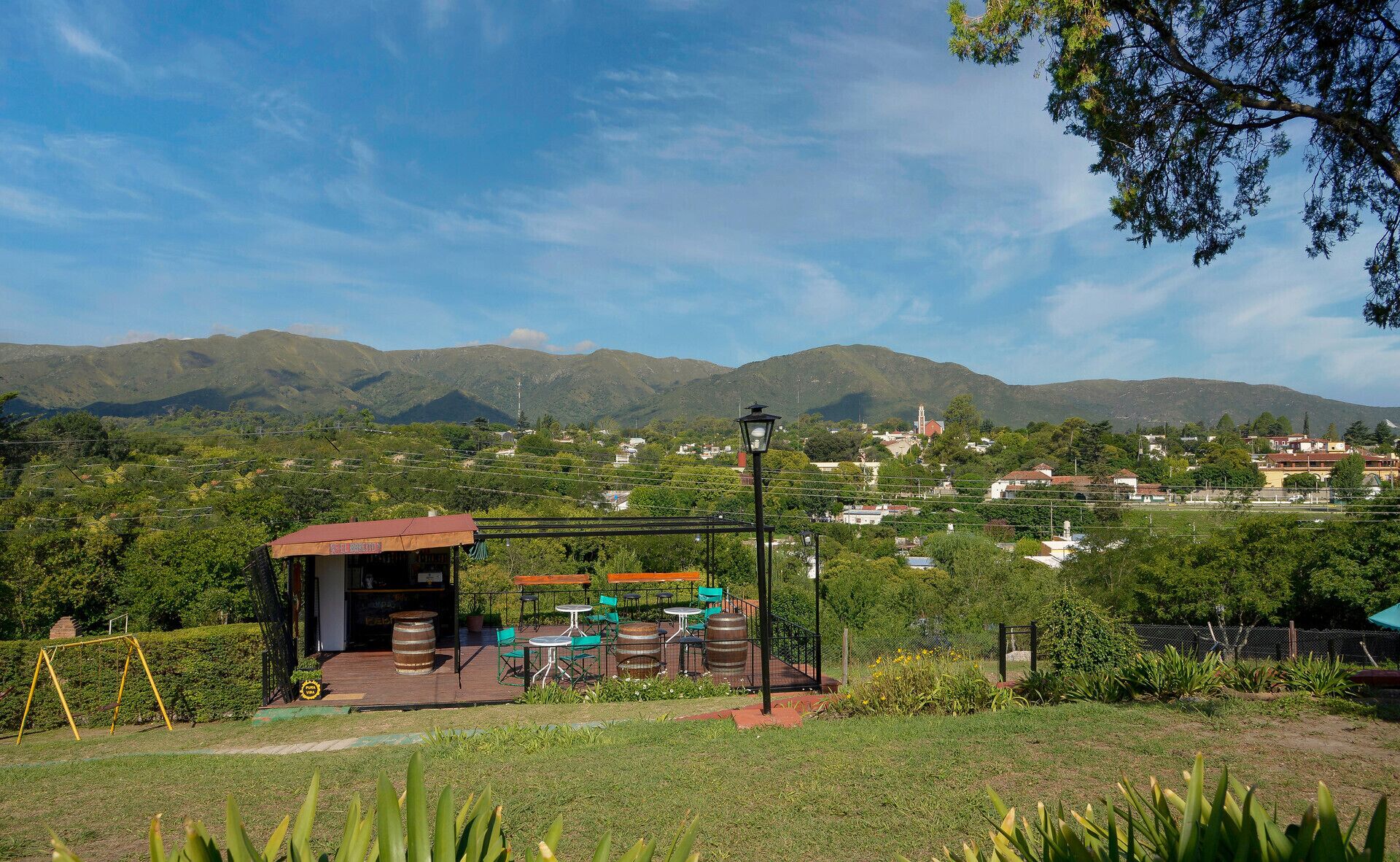 Eine Terrasse mit Sitzgelegenheiten im Freien und Blick auf eine Stadt und Berge im Hintergrund.