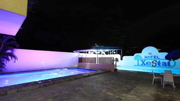 A hotel sign with a pool area, stone flooring, and outdoor seating.