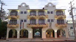A hotel with a central entrance, multiple balconies, and a sign indicating it is a hotel. - Hotel Xestal (Santa María Huatulco)