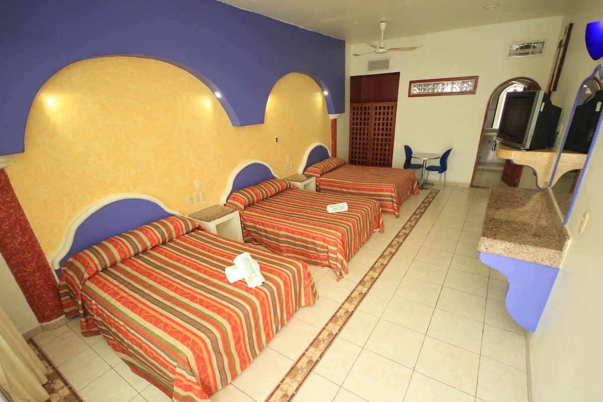 Une chambre d’hôtel avec trois lits, une télévision et un petit coin salon.