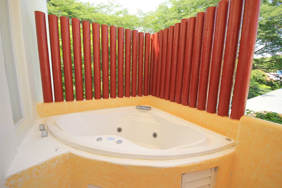 Un bain à remous à l’extérieur jaune, entouré d’une clôture rouge.