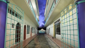 A hotel corridor with a stone floor, green metal railings, and a view of the sky through the ceiling. - Hotel Xestal (Santa María Huatulco)