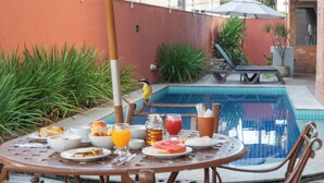 A round table with breakfast items and a bird on the edge. - Ritz Plazamar Hotel (Maceió)