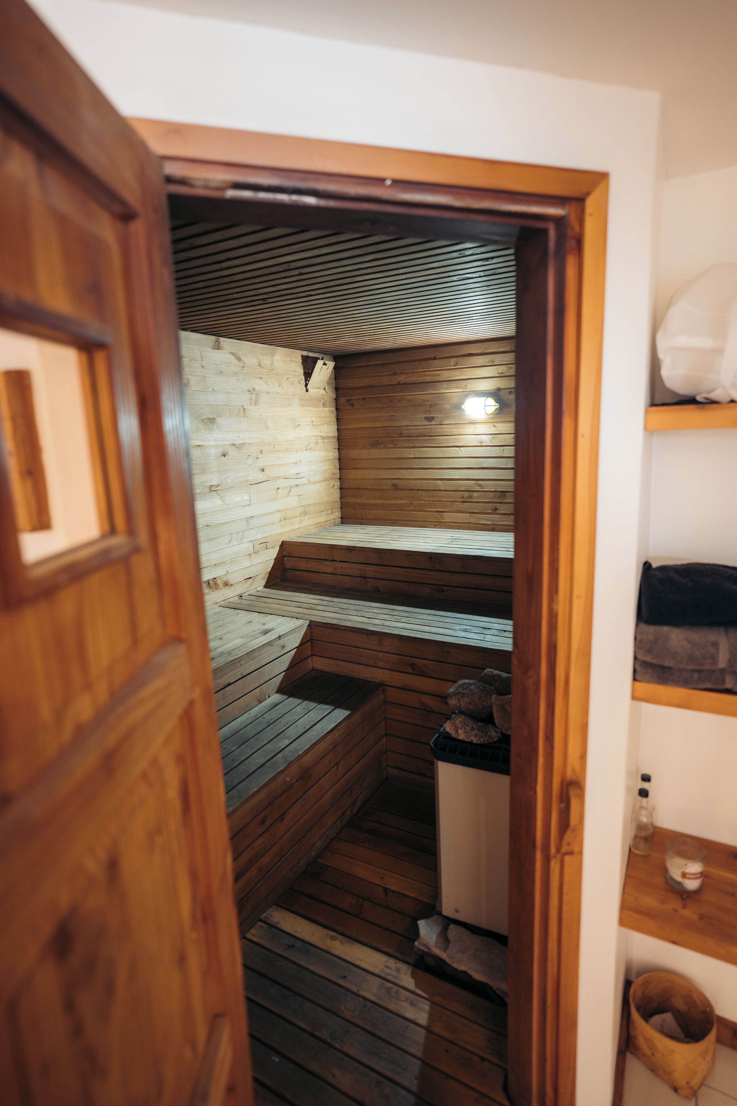 A sauna room with wooden benches and a bench in the center. There is a wooden door leading to the room.
