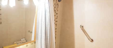 Un baño con techo de madera, un lavamanos blanco, una bañera y una ducha con cortina.