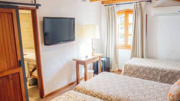 Un dormitorio con dos camas, vigas de madera, un televisor, un escritorio y una ventana con cortinas.