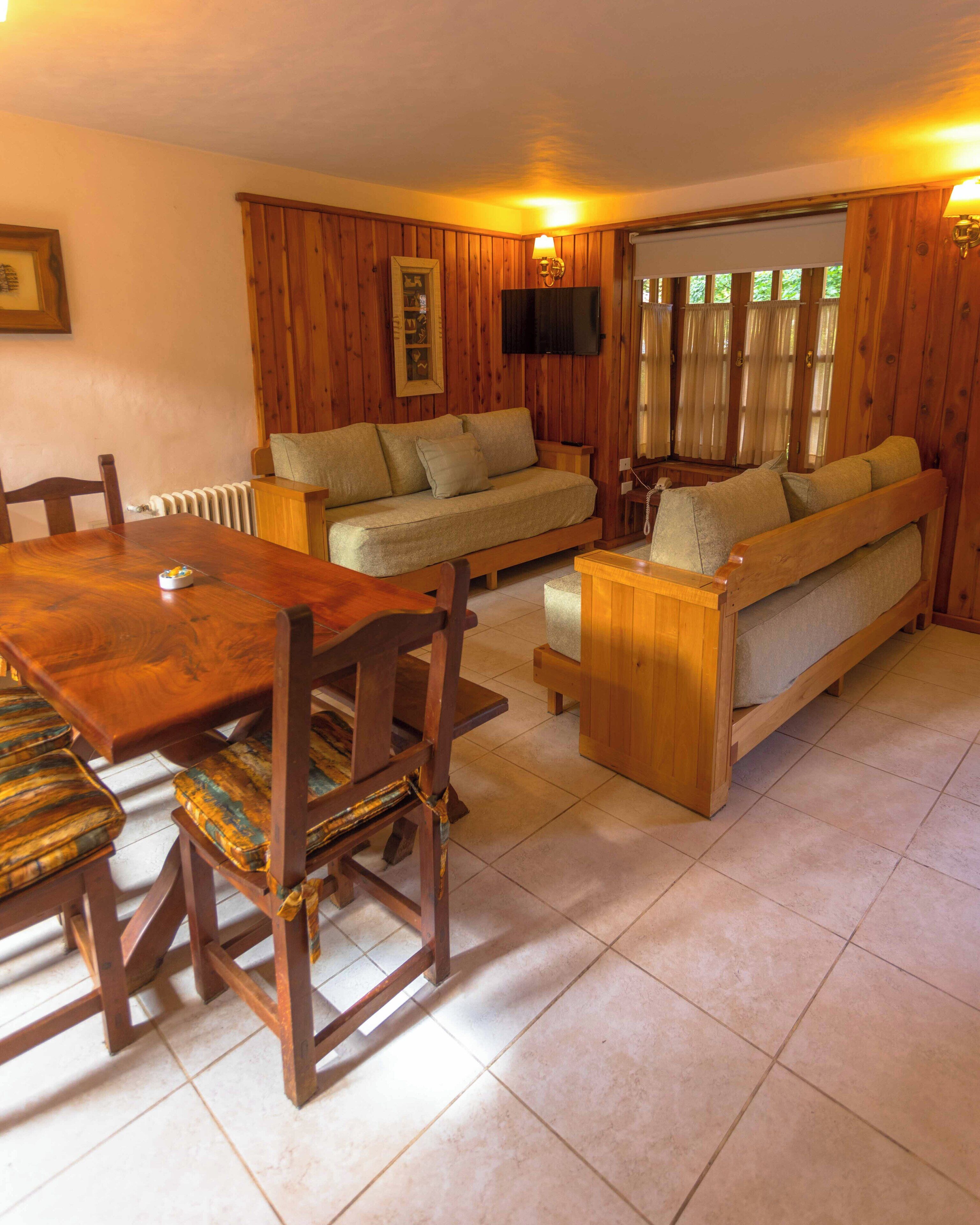 A cozy living room with a wooden dining table, a sofa, and a bench.