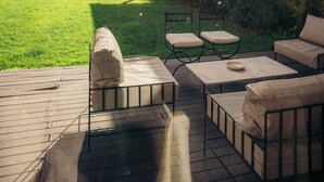 Un patio con mobiliario exterior, un muro de piedra y vistas a una casa y montañas.
