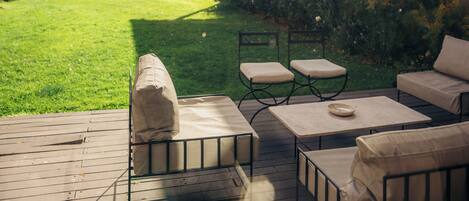 Eine Terrasse mit Gartenmöbeln, einer Steinmauer und Blick auf ein Haus und Berge.