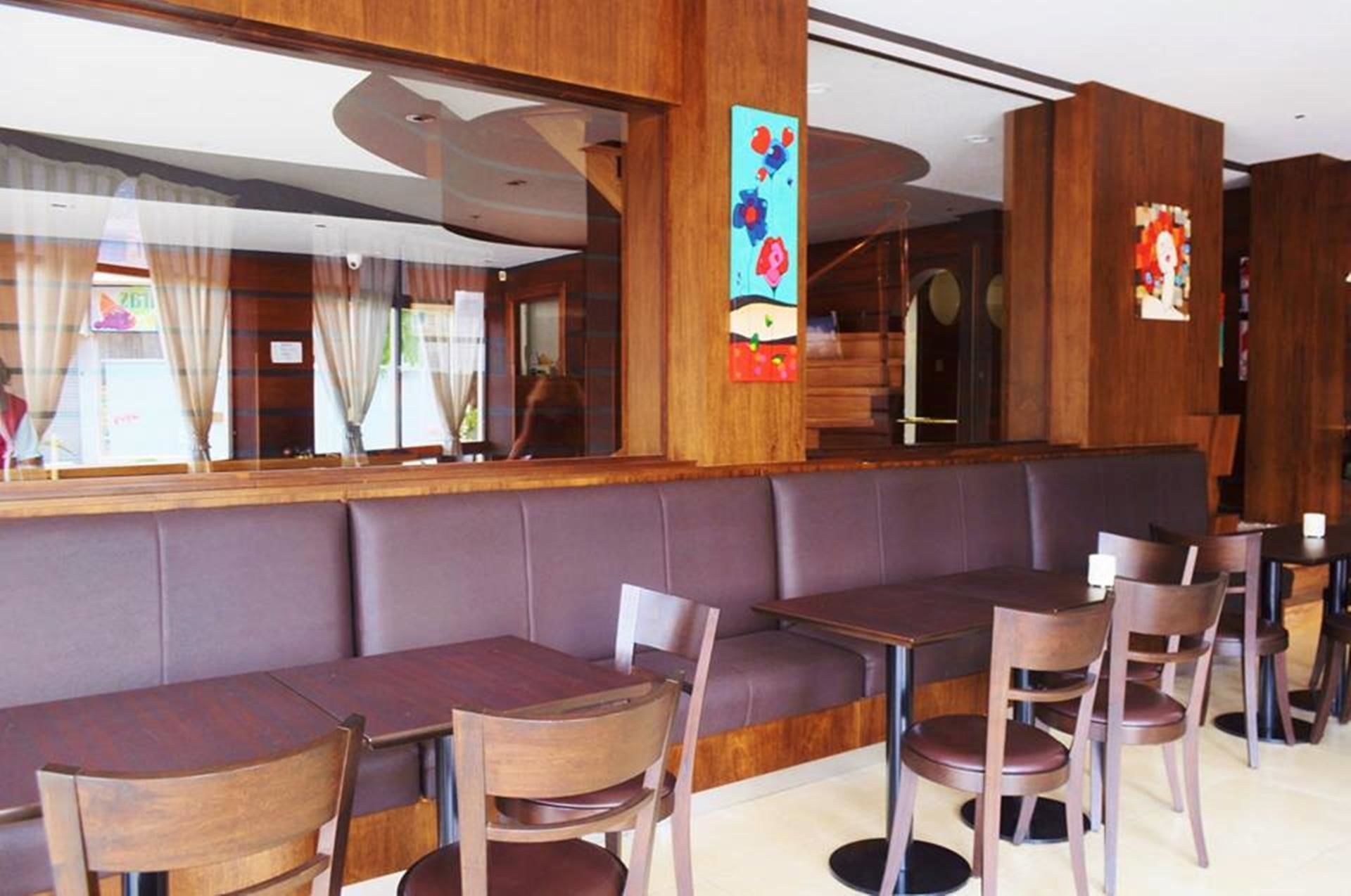 A restaurant with wooden paneling, cushioned booths, and wooden chairs.