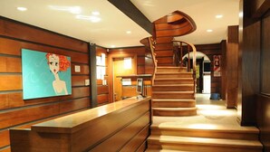 A wooden reception desk with a spiral staircase leading to upper floors. - Don Carlos Hotel (Villa Gesell)