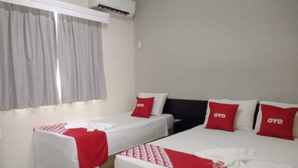A hotel room with two beds, each with red and white bedding, and a window with curtains. - Cerrado Hotel (Campo Grande)