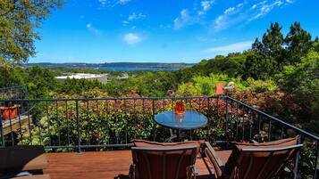 Relax on the balcony with a panoramic view of the lush landscape and distant water.