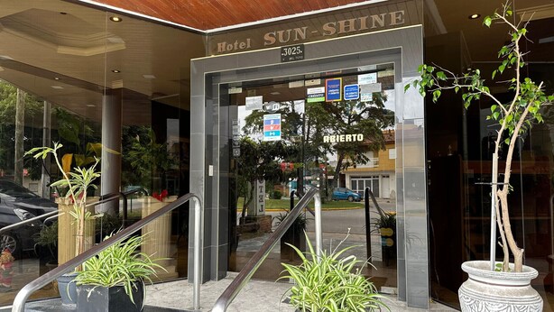 The entrance to Hotel Sun-Shine, featuring a modern design with glass doors, metal railings, and potted plants. - Hotel Sun Shine (San Clemente)