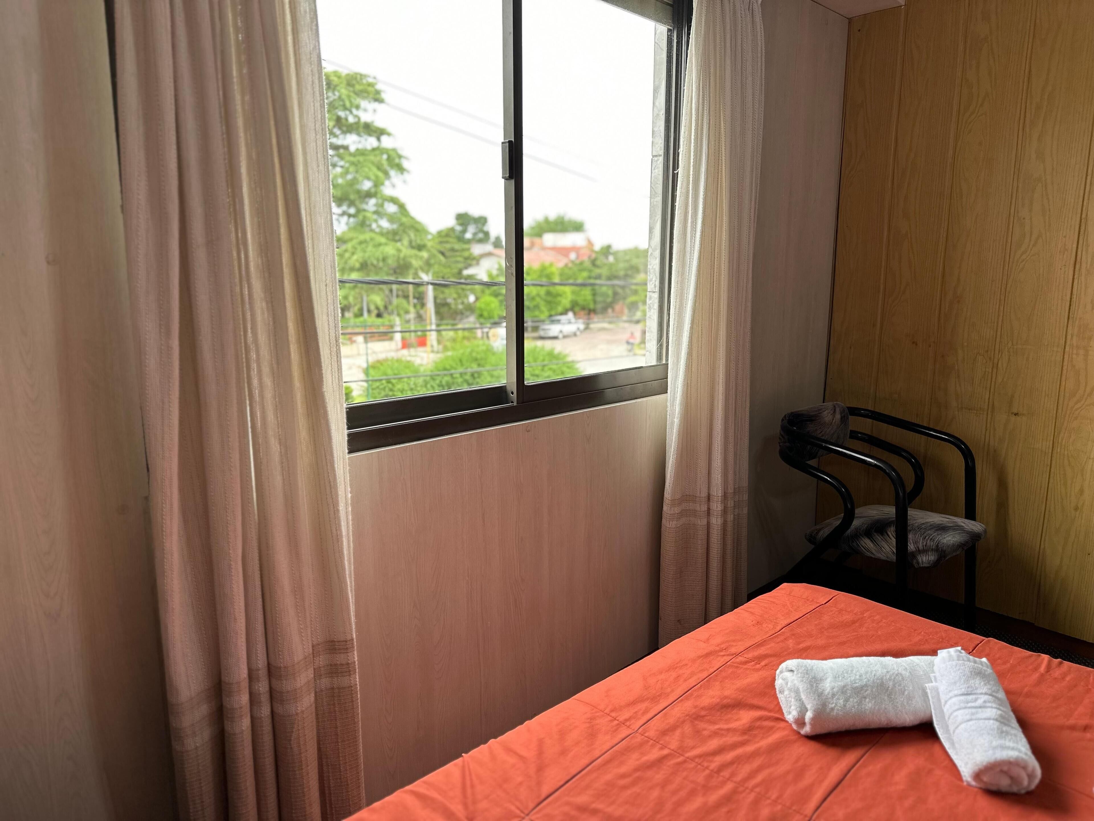 A room with a bed, a chair, and a window with curtains.