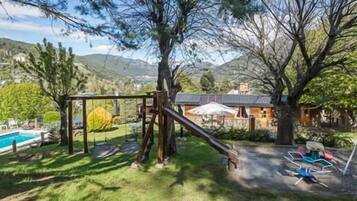 Relax in a serene outdoor setting with a well-maintained lawn, swing set, and pool.