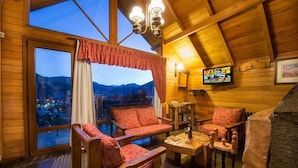 A cozy wooden cabin interior with a large window overlooking a mountainous landscape. - Cabañas y Apart Antuen (San Martin de los Andes)