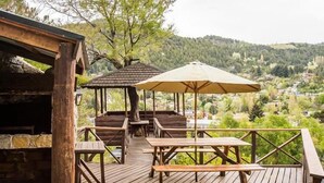 A wooden deck with picnic tables and a gazebo, overlooking a valley with houses and trees. - Cabañas y Apart Antuen (San Martin de los Andes)