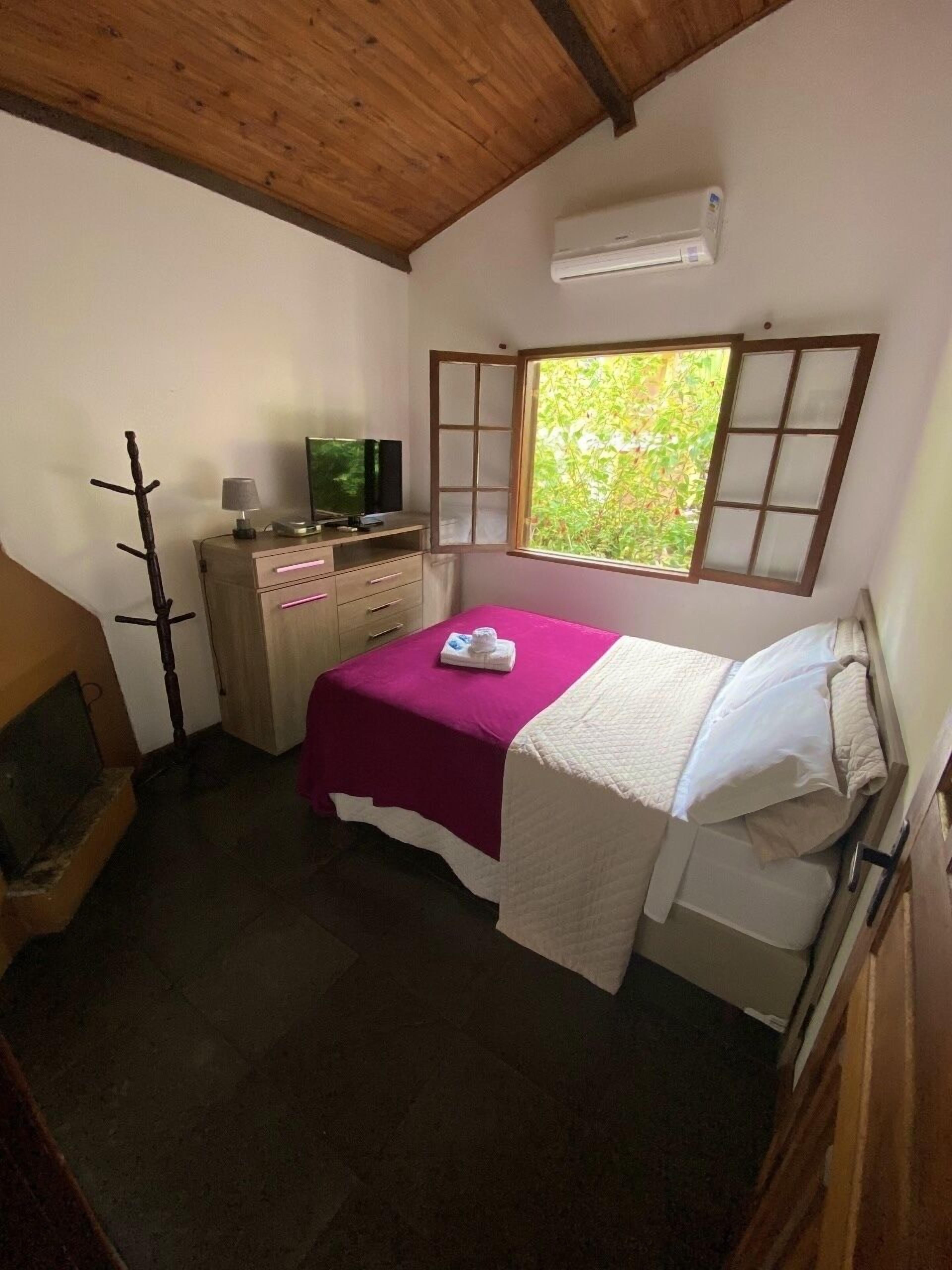 Un dormitorio con cama, televisión, escritorio y ventana.
