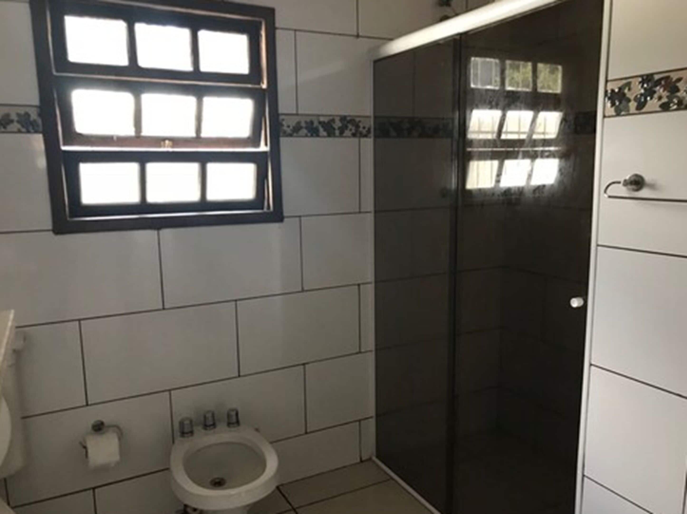 Une salle de bain comprenant des toilettes, un bidet et une cabine de douche en verre.