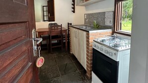Une cuisine de taille réduite, équipée d’une cuisinière à gaz, d’un évier et d’une fenêtre.