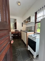 Una cocina compacta con estufa a gas, un lavamanos y una ventana.
