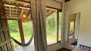 Une chambre avec un lit, un hamac et une vue sur l’extérieur.