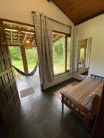 Un dormitorio con cama, una hamaca y vistas al exterior.
