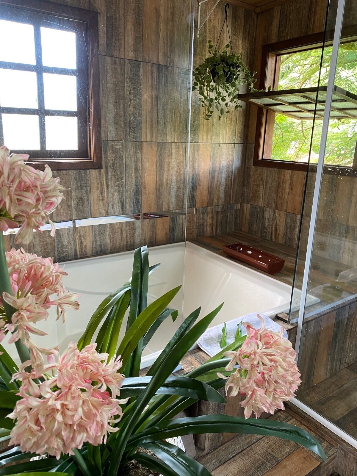 Un baño con bañera, cabina de ducha de vidrio y pared de madera.
