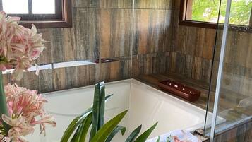 Un baño con bañera, cabina de ducha de vidrio y pared de madera.