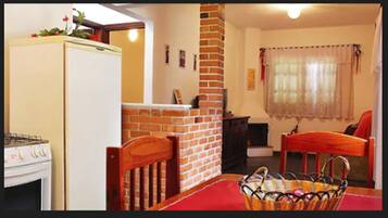 Una cocina compacta con refrigerador, estufa y chimenea de ladrillo.