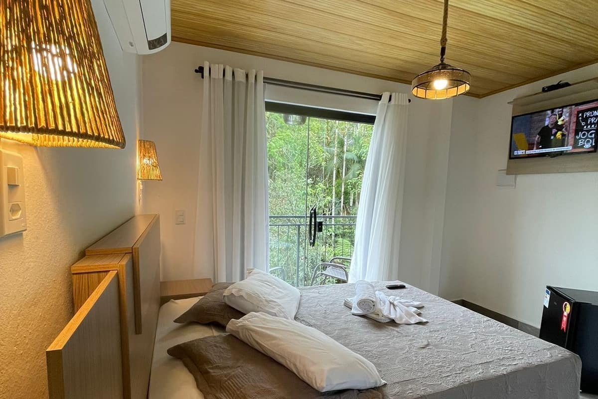A modern bedroom with a bed, bedside lamps, a ceiling fan, and a window with curtains.