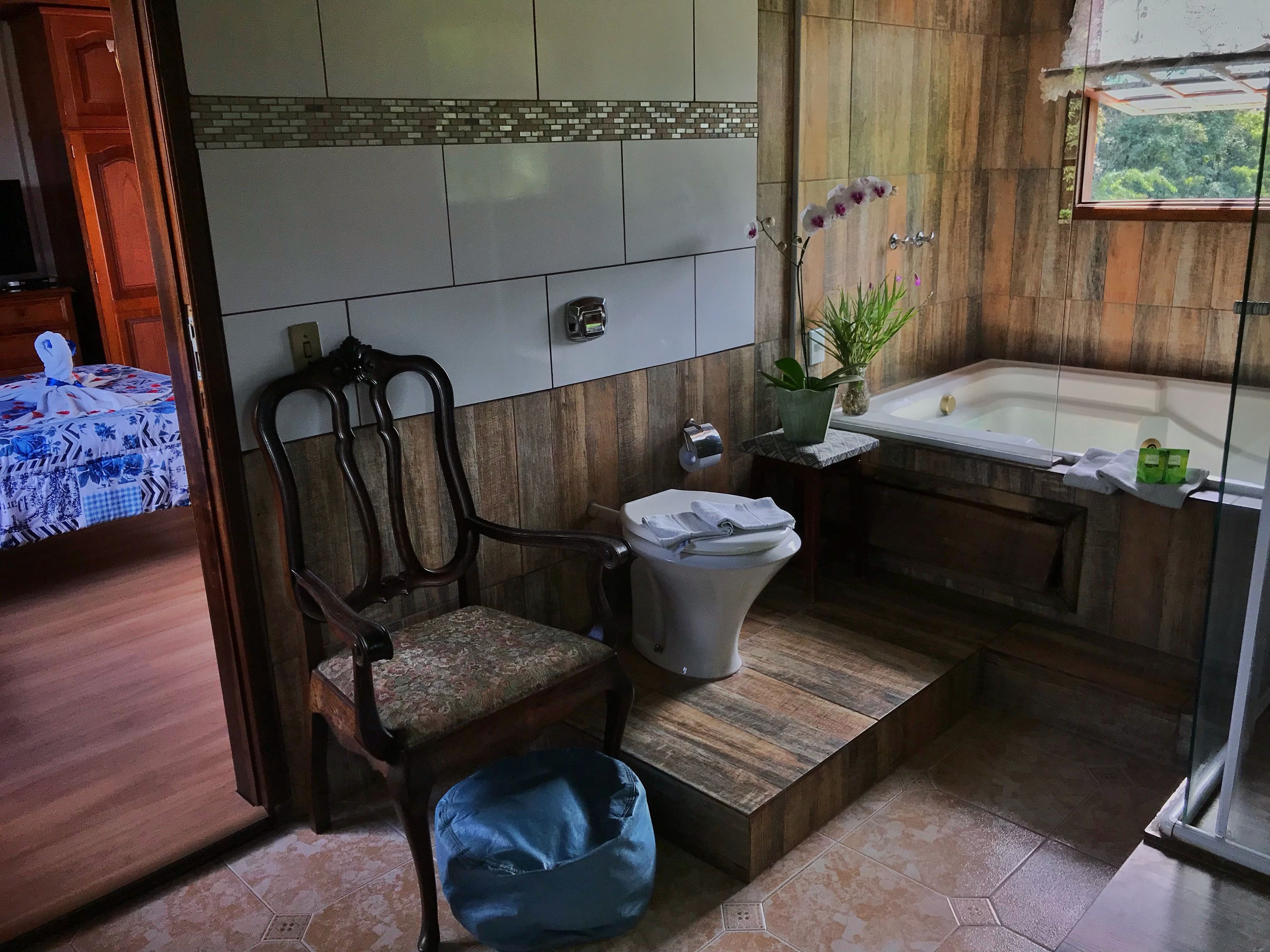 A bathroom with a wooden vanity, a toilet, a bathtub, and a chair.