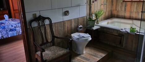 A bathroom with a wooden vanity, a toilet, a bathtub, and a chair.