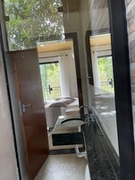 Un baño moderno con un espejo grande, un lavamanos y una zona de ducha.