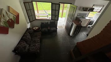 Una sala de estar con sofá, un comedor con mesa y sillas, y una cocina con estufa y fregadero.