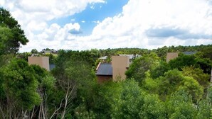 A rectangular swimming pool with a wooden deck, surrounded by lush greenery and trees. - Oasis Apart Hotel (Mar Azul)