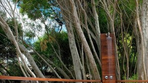 A wooden deck with white plastic lounge chairs, surrounded by trees and a wooden fence. - Oasis Apart Hotel (Mar Azul)