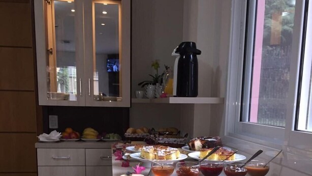A kitchen with a dining table set for a meal, featuring various dishes and a coffee maker.