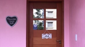 A wooden door with a heart-shaped sign on the wall to the left.