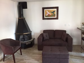 Ein Wohnzimmer mit Kamin, einer Couch, einem Hocker und einem Sessel.