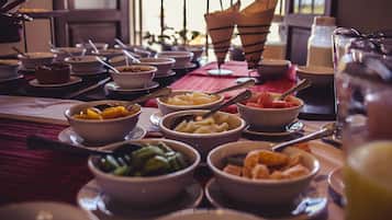 Uma mesa posta com várias tigelas de comida, incluindo frutas e legumes, e um jarro de vidro.