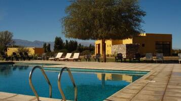 Una piscina al aire libre, sillones reclinables de piscina
