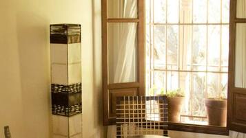 Una habitación con un ventanal grande, una silla, una mesa y un adorno alto.