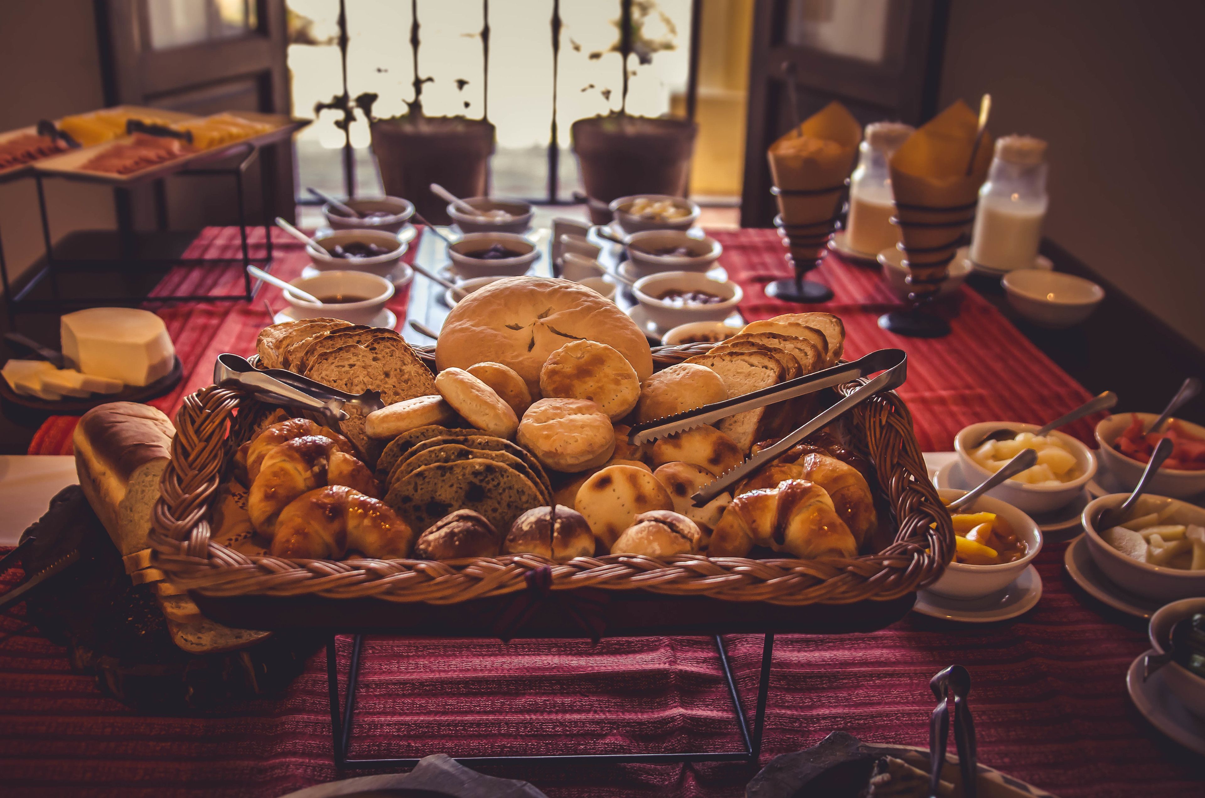 Una mesa de buffet con panes, pasteles y salsas variadas.